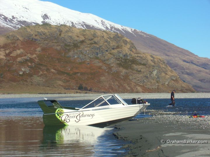 The Wanaka River Journeys jetboat parked on the Matukituki River; host Brent standing in river